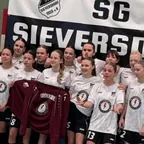 Drużyna piłkarska SG Sieversdorf przed klubowym banerem, z przodu ciemnoczerwona koszulka